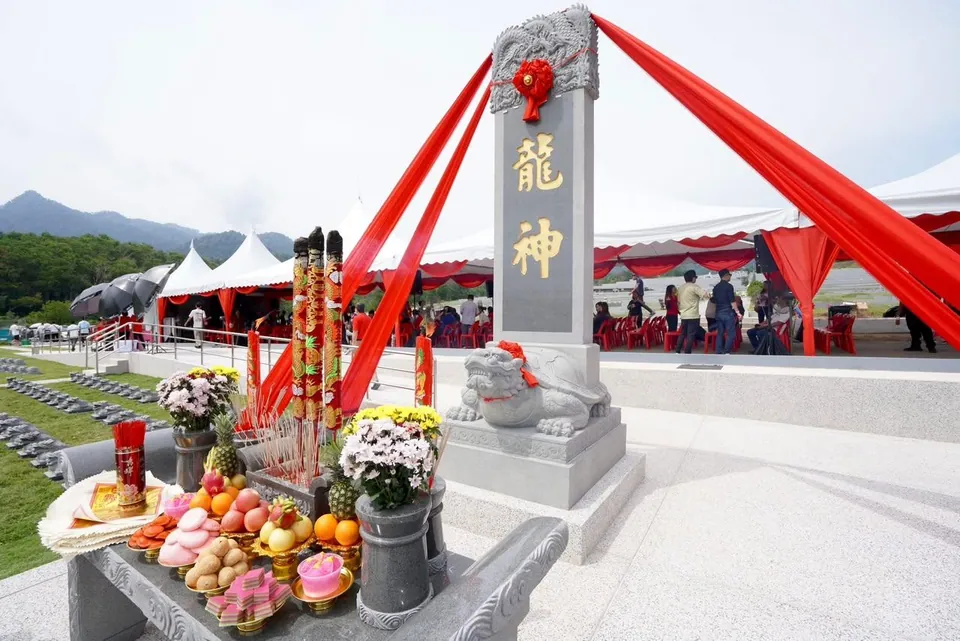 龙神碑前的供桌：鲜花、水果与香烛，后面是红白帐篷