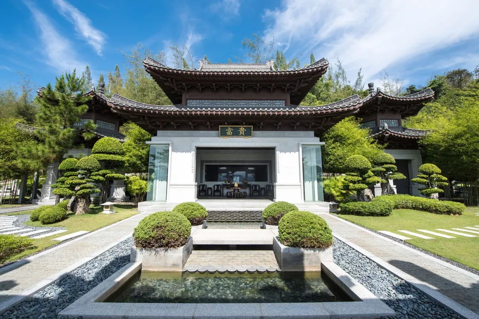 士毛月富贵山庄皇家墓园照片：中式门楼前的水池与修剪整齐的松树